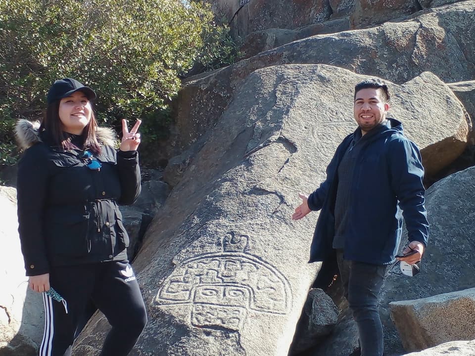 Visitantes junto a un petroglifo en el Valle del Encanto